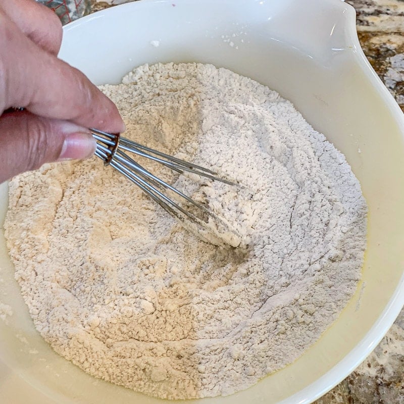whisking flour in a white bowl
