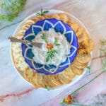 jajik cream cheese dip in a blue bowl with crackers