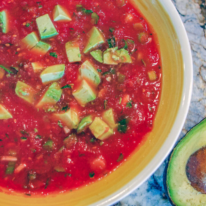 mexican salsa in a bowl with a yellow rim and a sliced avocado on the side