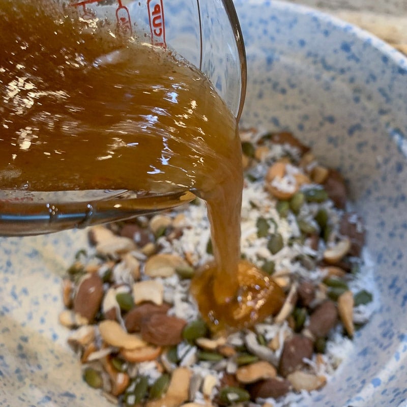 pouring honey on nut cluster mix