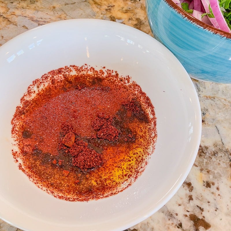 sumac onions dressing in a bowl with blue bowl behind it