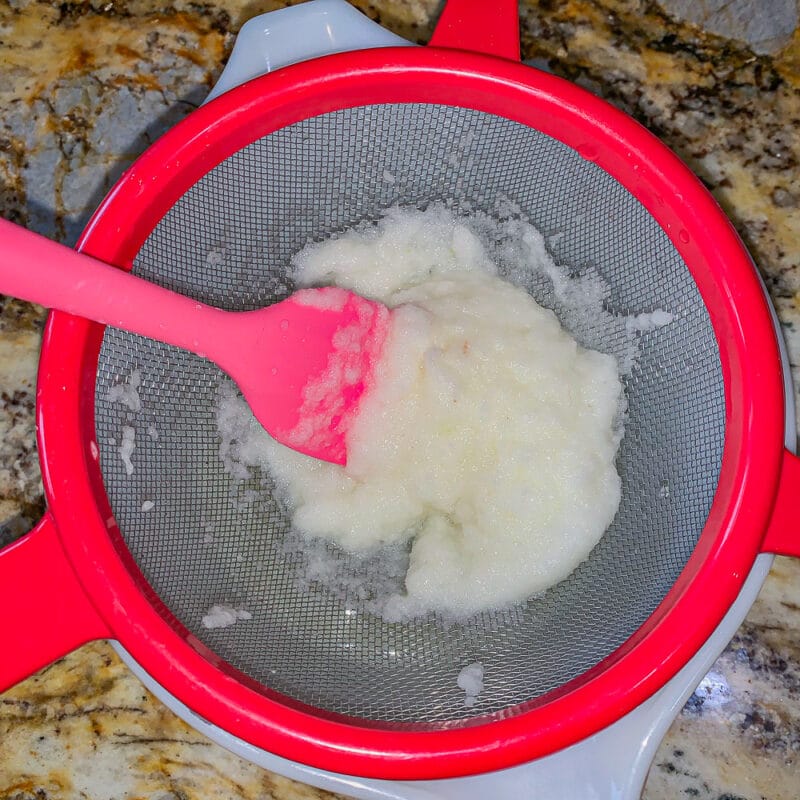 pureed onion in a red strainer