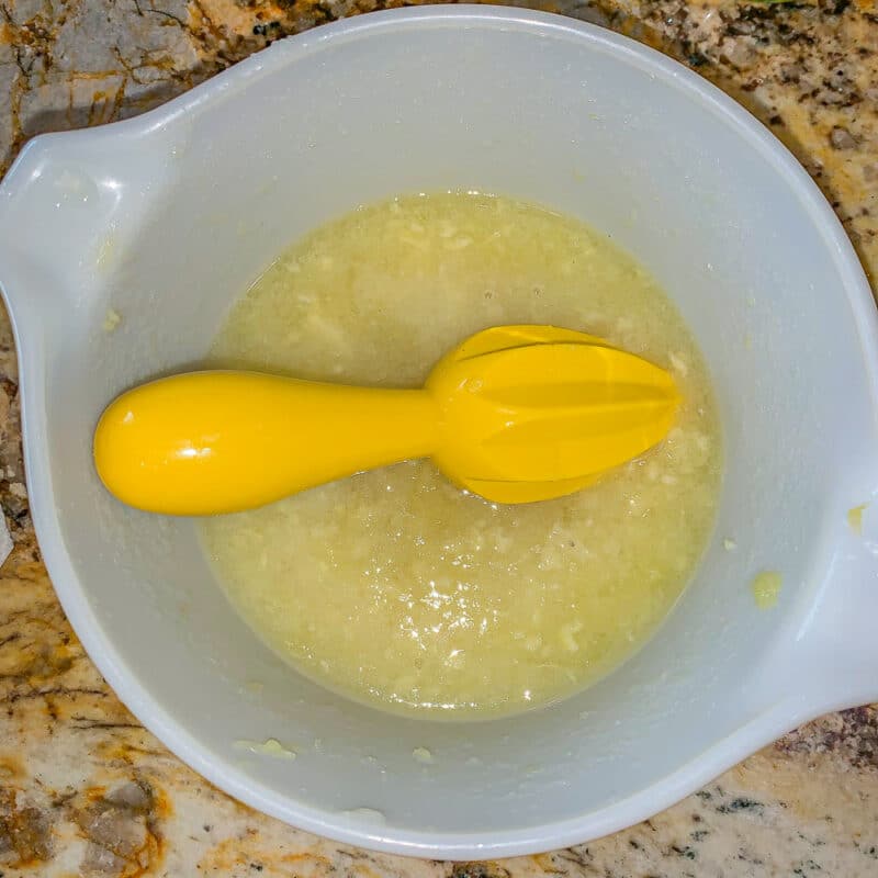 lemon juice and juicer in a white glass bowl