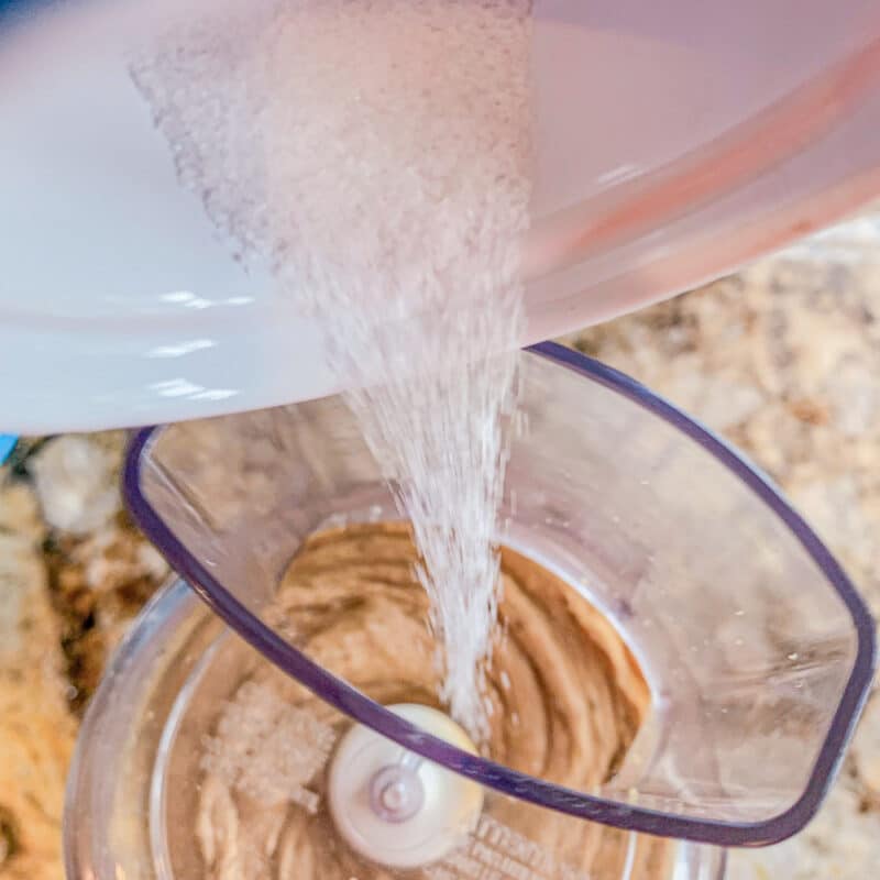 adding salt to food processor with blended chickpeas