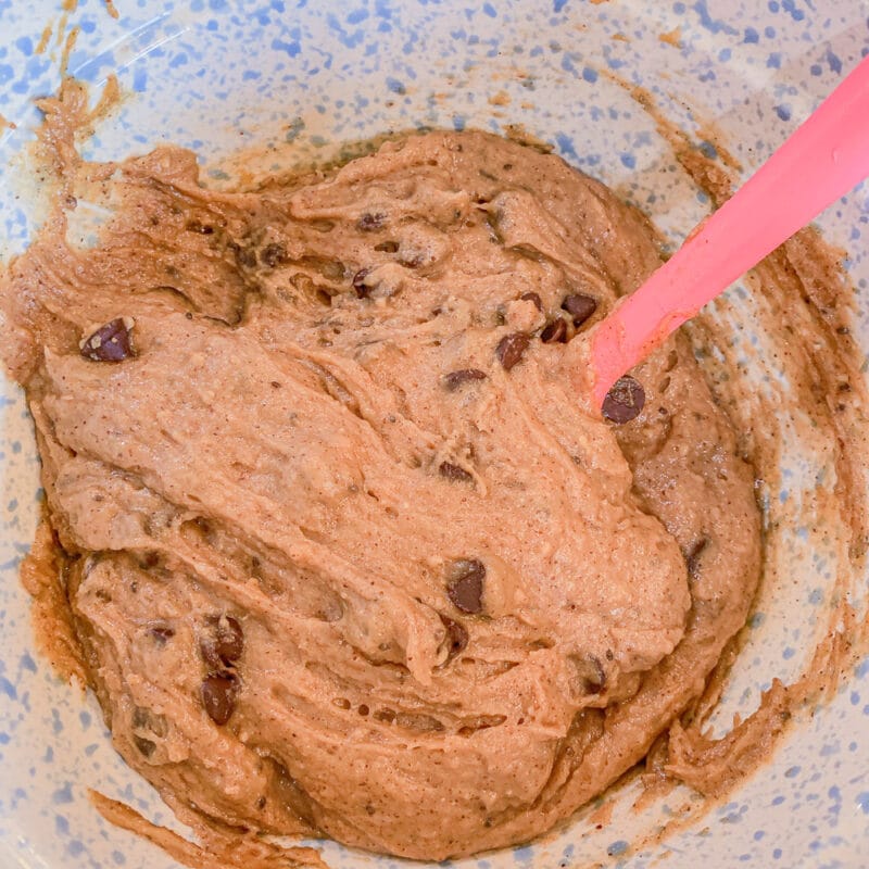 folding chocolate chips in chickpea cookie dough with a pink spatula 