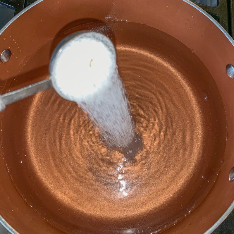 salt being poured into a pot of water