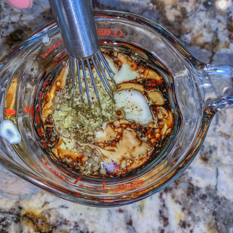 whisking salad dressing ingredients in a cup