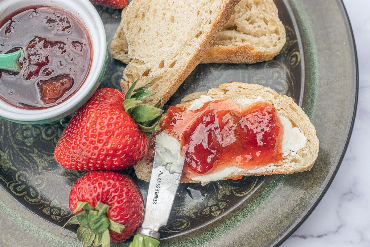 rhubarb strawberry jam on toast and fresh strawberries on a green plate