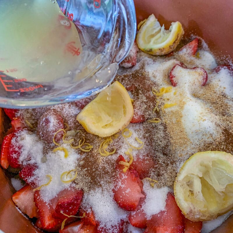 adding lemon juice to pot full of rhubarb strawberry jam ingredients