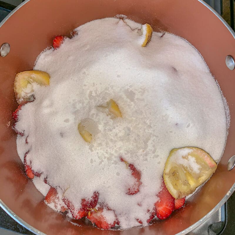 jam ingredients in a pot covered with a bunch of sugar