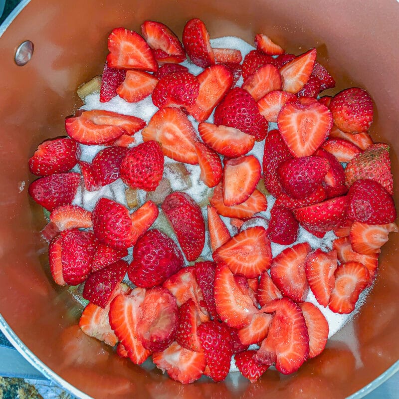 chopped strawberries and sugar in a brown pot