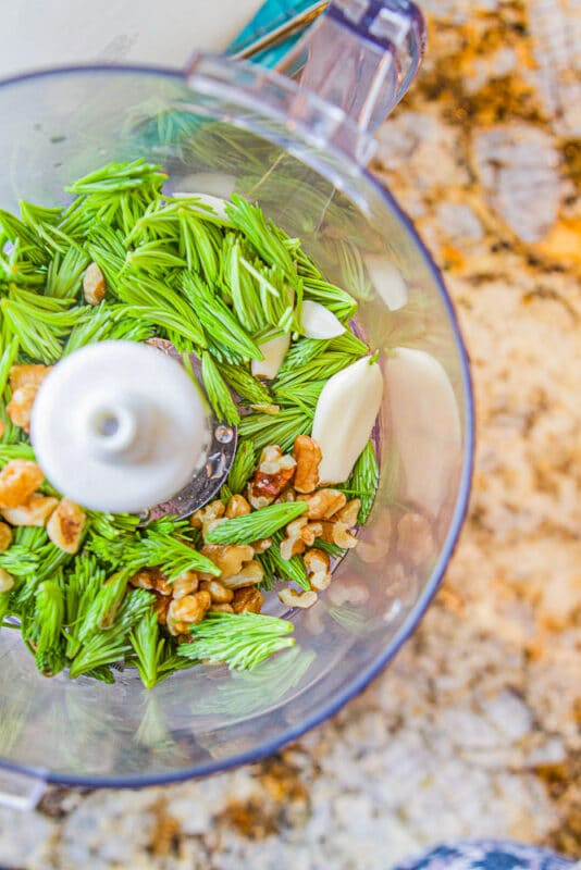 Food processor with spruce tips and garlic cloves