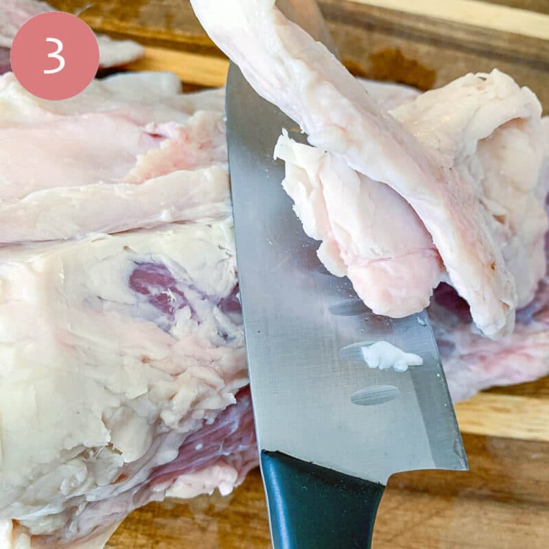 removing fat from tri-tip roast with a sharp knife on a cutting board