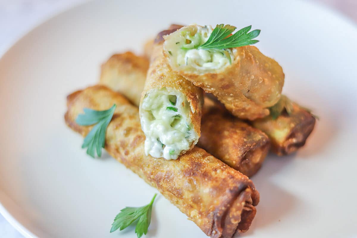 burek (eggrolls) on a white plate garnished with chopped parsley