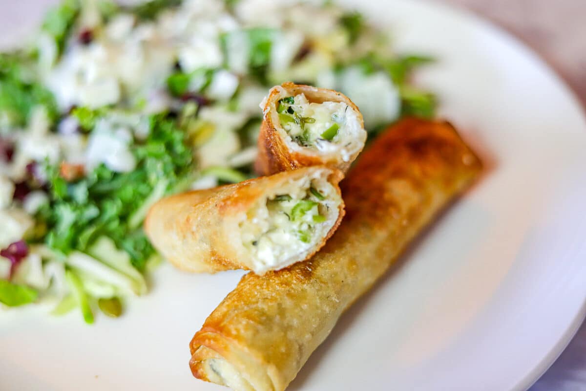 burek/egg rolls on a white plate with a salad