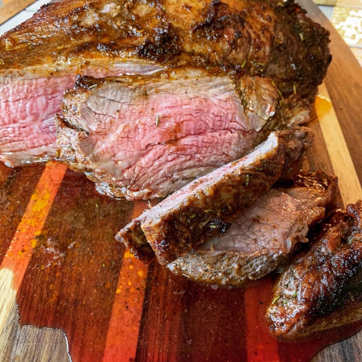 sliced medium rare oven trip roast on a cutting board