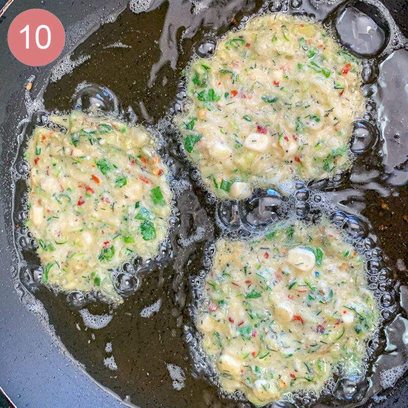 3 fritters frying in a pan
