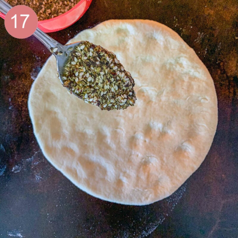 spooning zaatar paste onto raw dough to make manaqish