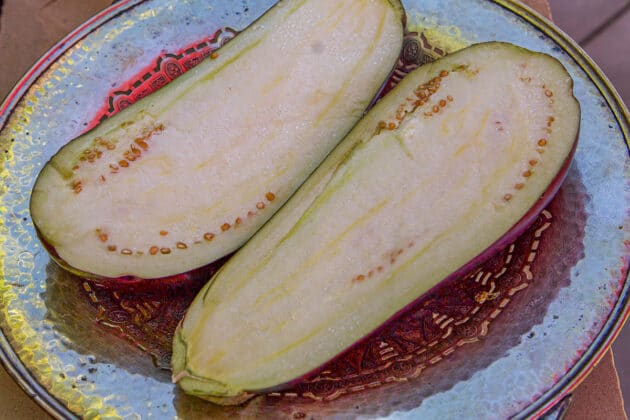 one eggplant sliced in half on a silver dish