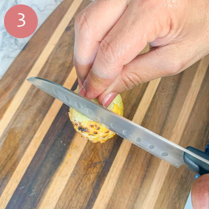 cutting corn off the cob over a cutting board