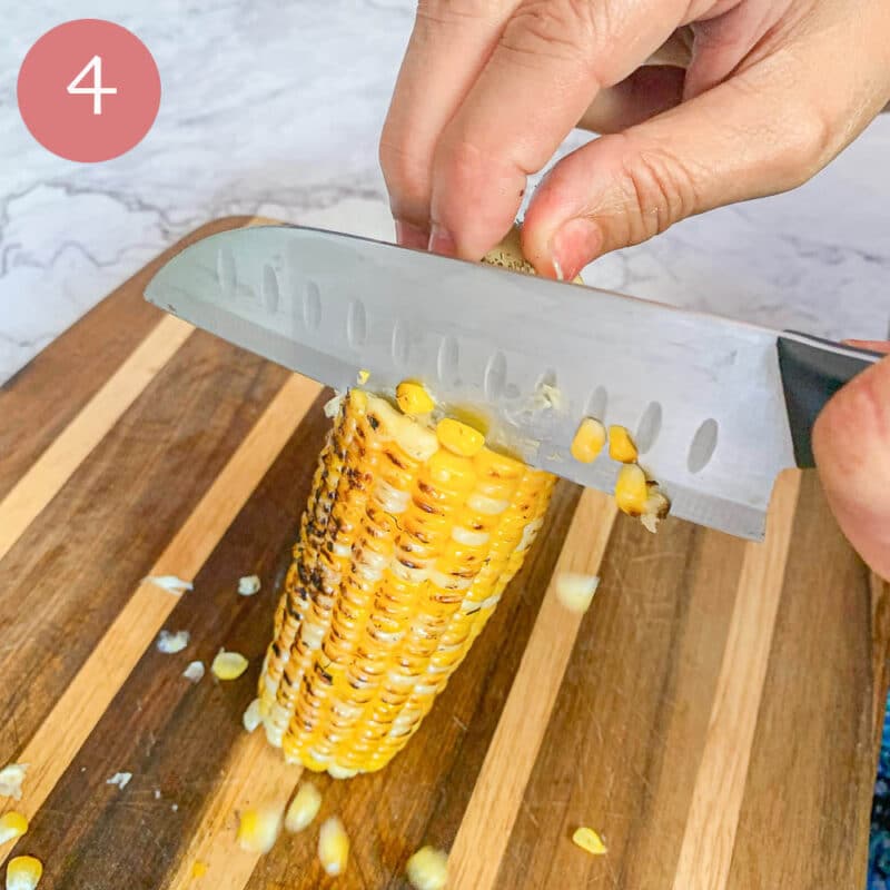 slicing corn off the cob over a cutting board