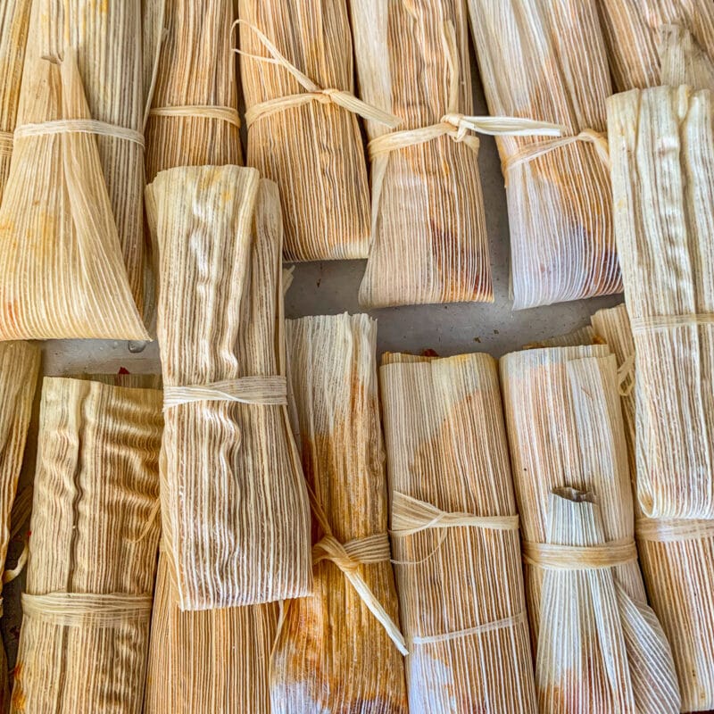 a bunch of wrapped tamales on a tray