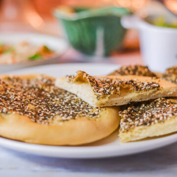 Manakish flat bread on a plate with other dishes behind it