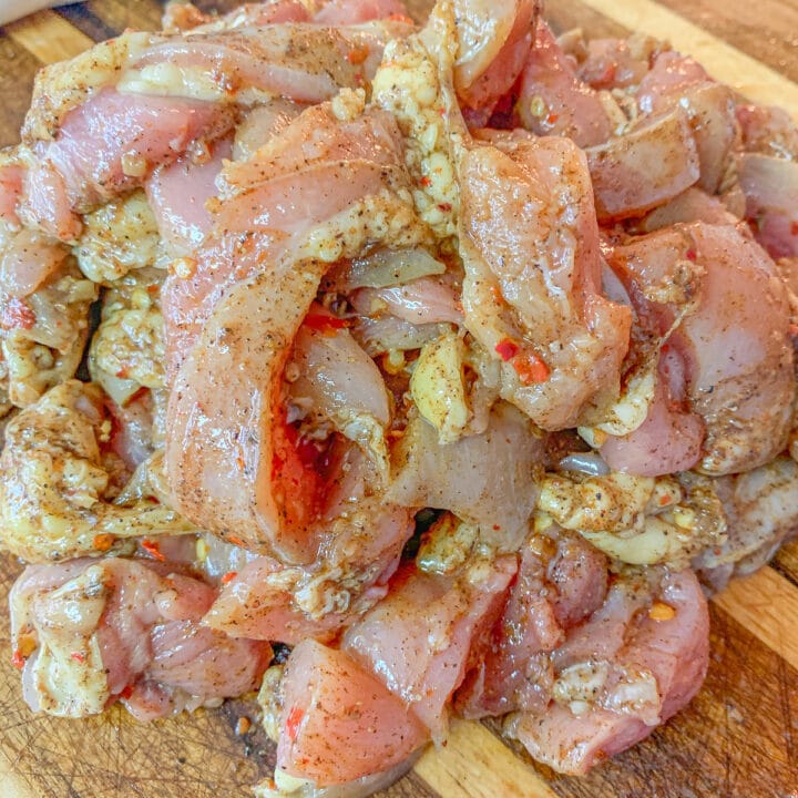 seasoned raw chicken strips on a cutting board