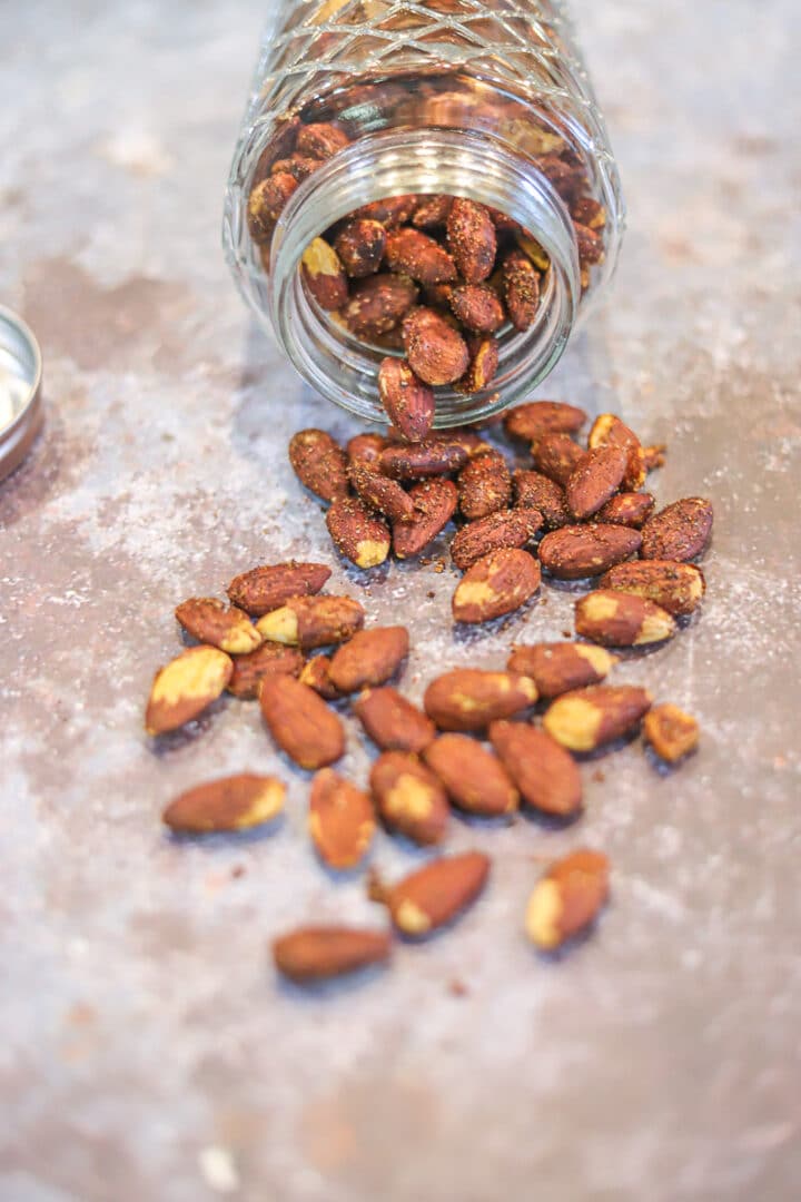 spicy toasted almonds spilling from a jar onto the counter