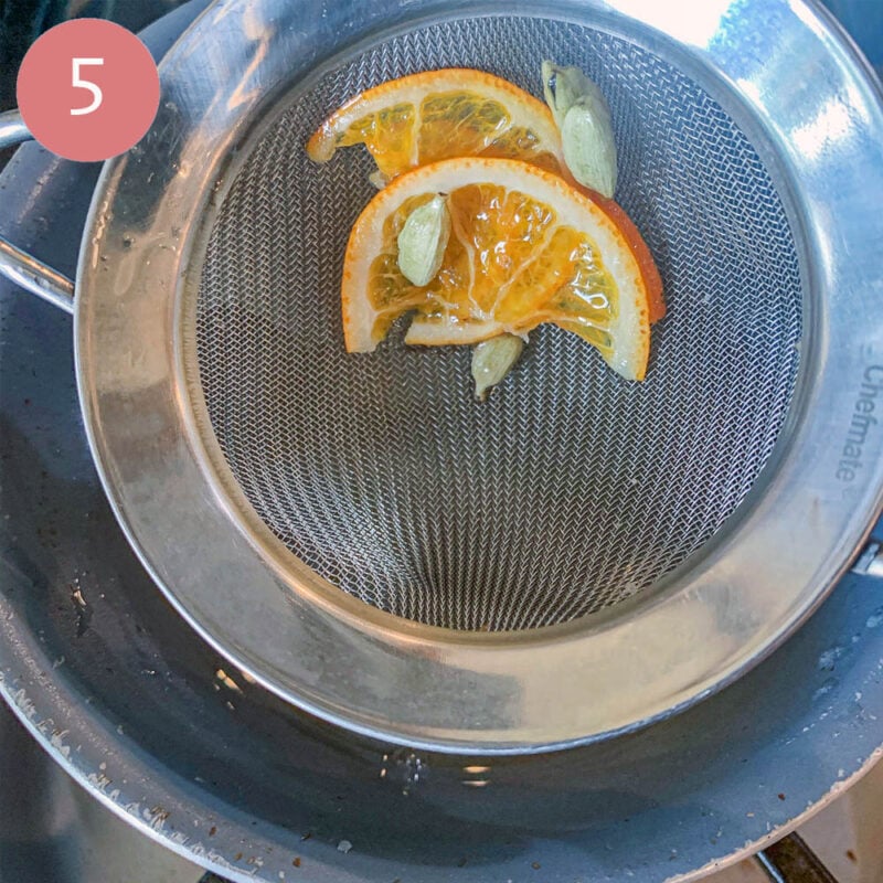staining orange slices and cardamom pods over a saucepan