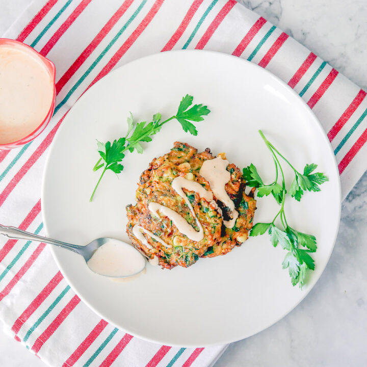 New Years eve appetizers: zucchini fritters on a white plate over a striped white, red, and green napkin