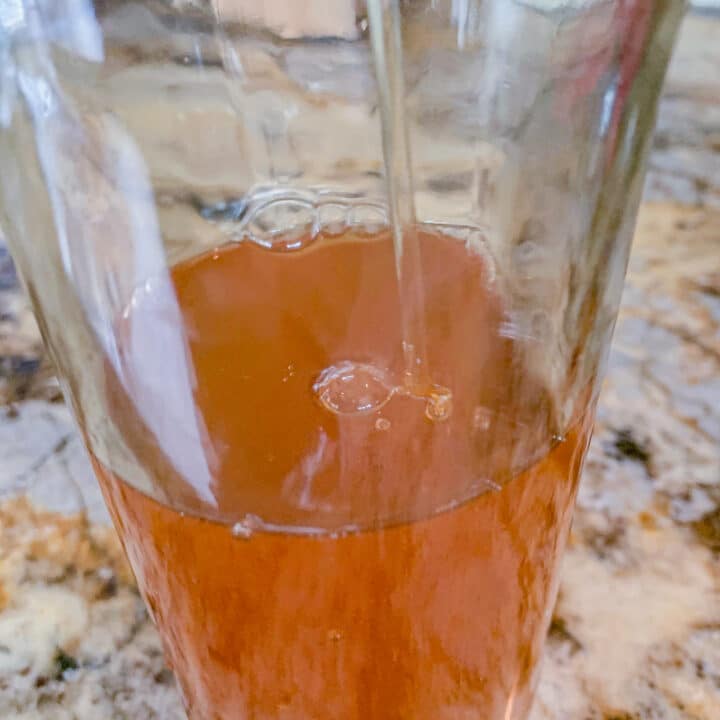pouring rose hip syrup into a bottle