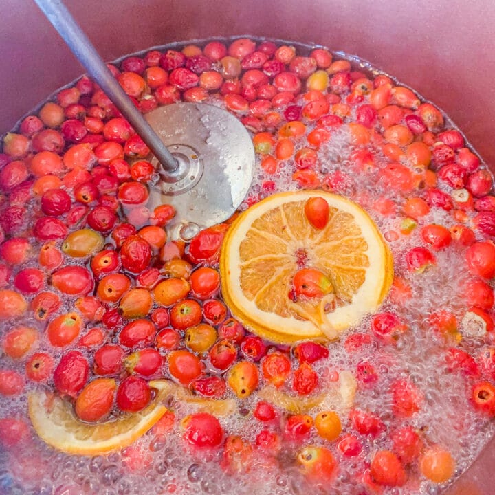 mashing rosehips in a pot with a masher