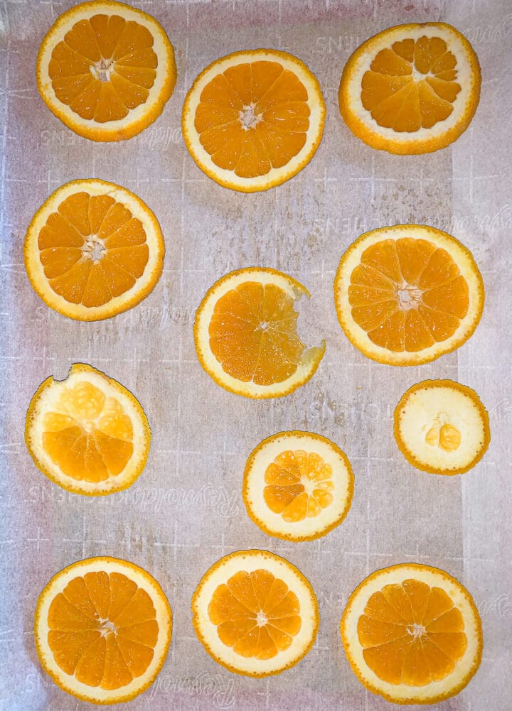 orange slices arranged of a cookie sheet lined with parchment paper