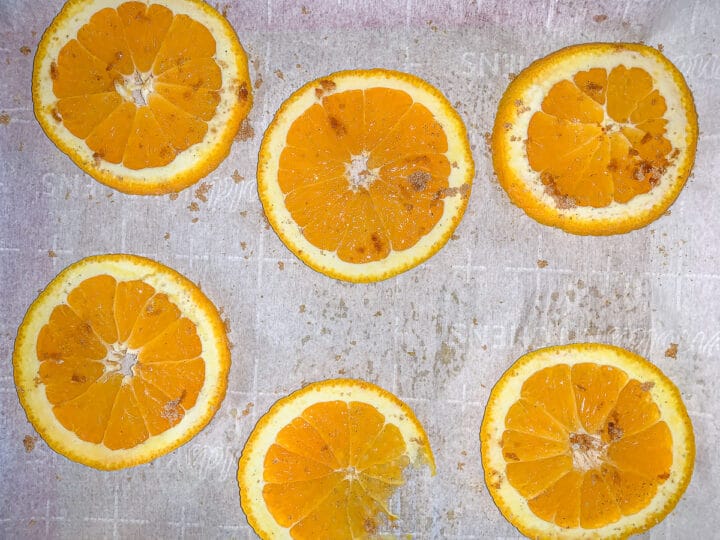 orange slices sprinkled with brown sugar arranged of a cookie sheet lined with parchment paper.