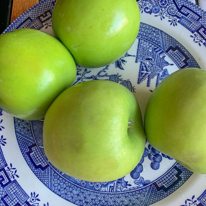 four apples on a blue willow plate