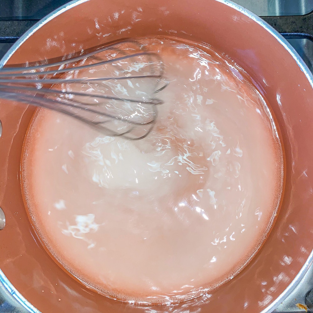 sugar and water being whisked in a pot