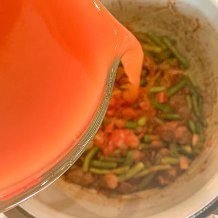 tomato sauce being poured over fasolia stew