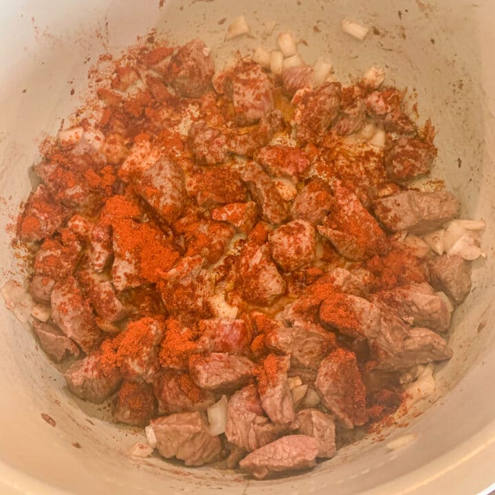 stew meat and onions sprinkled with paprika in an instant pot