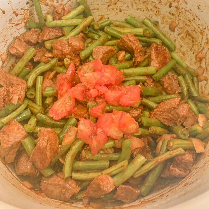 stew meat and green beans covered with diced tomatoes in an instant pot