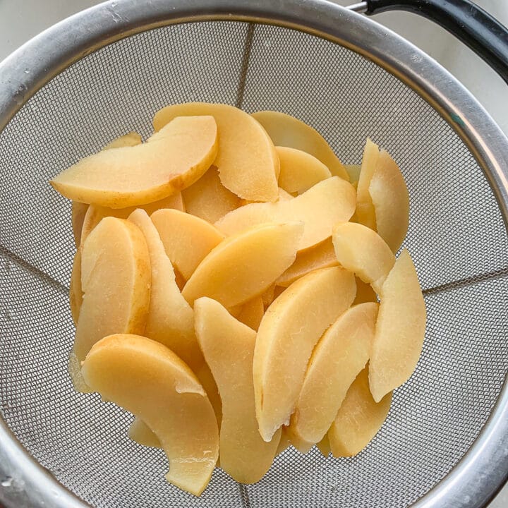sliced cooked quince draining in a strainer