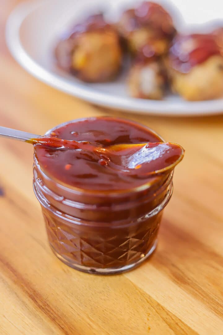 bbq sauce in a jar with chicken in the background