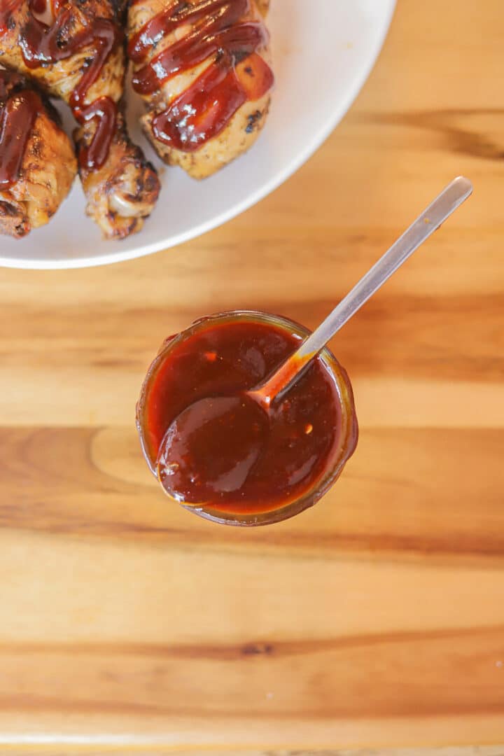 bbq sauce in a jar with some bbq chicken on a plate