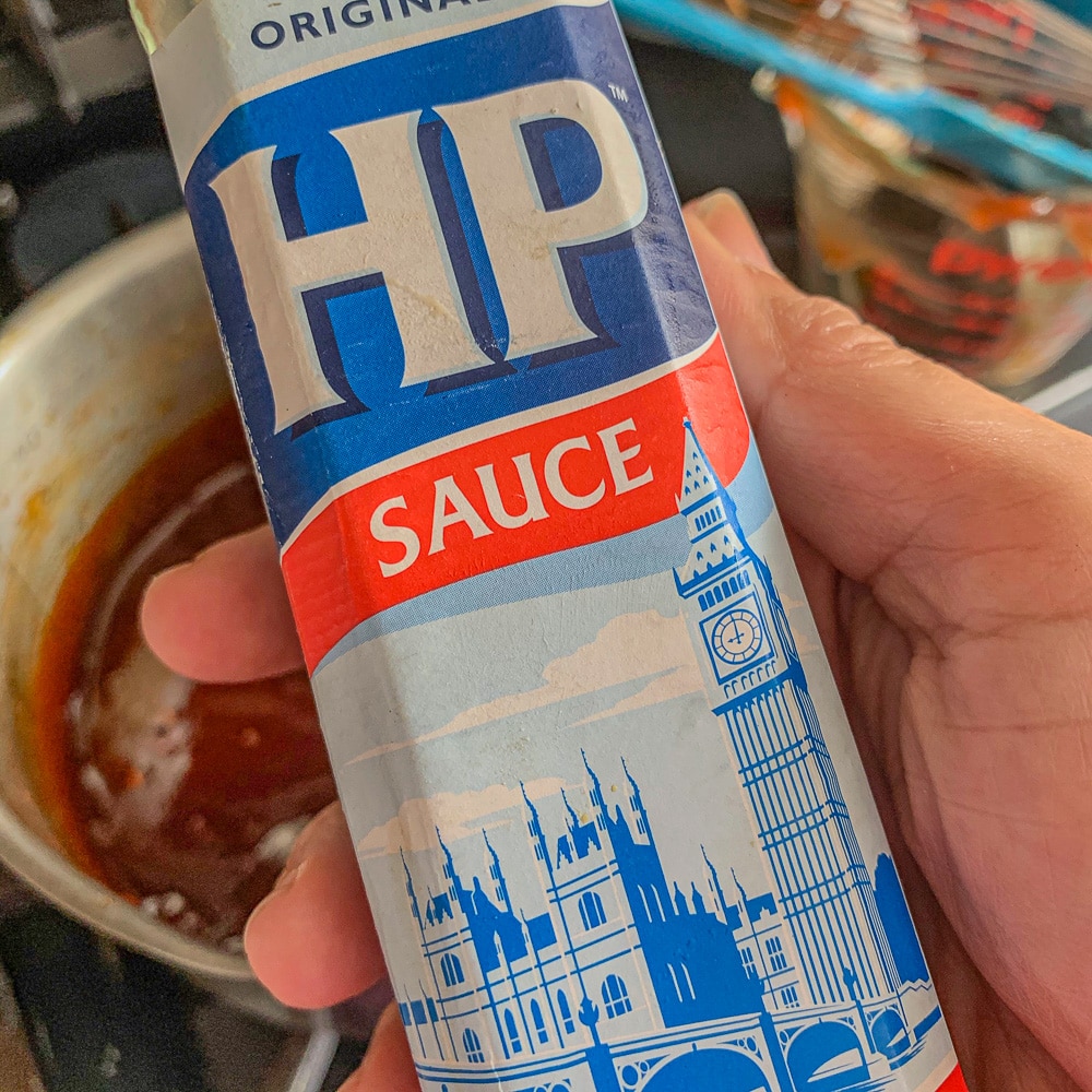 hp sauce bottle being held over a pot of sauce