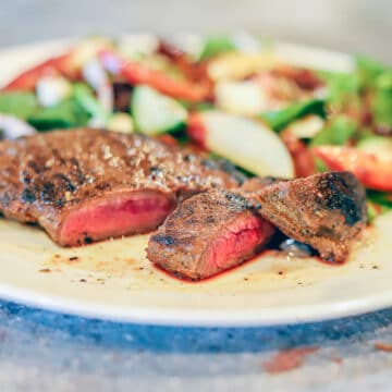 elk steak and salad on a white plate