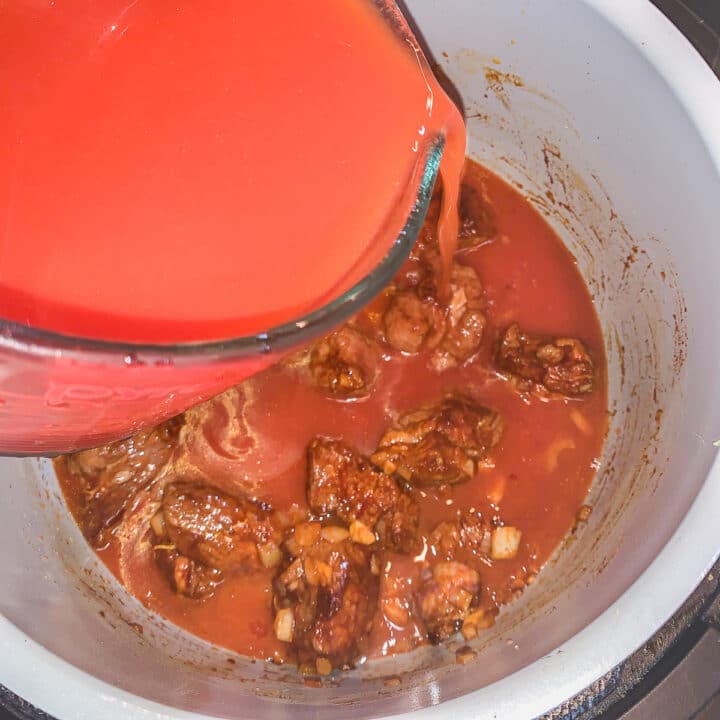 tomato sauce being poured over stew in an instant pot