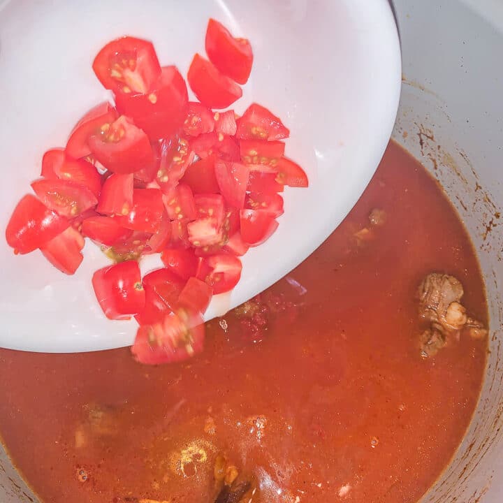 adding tomatoes to a stew