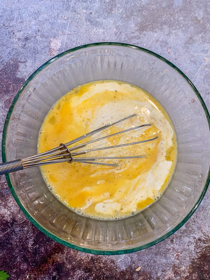 eggs and cream whisked in a glass bowl