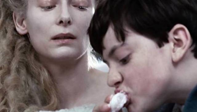 Edmund eating candy white the witch looks over his shoulder