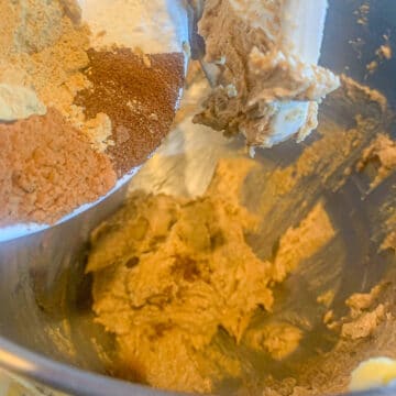 adding spices to a bowl of cookie dough